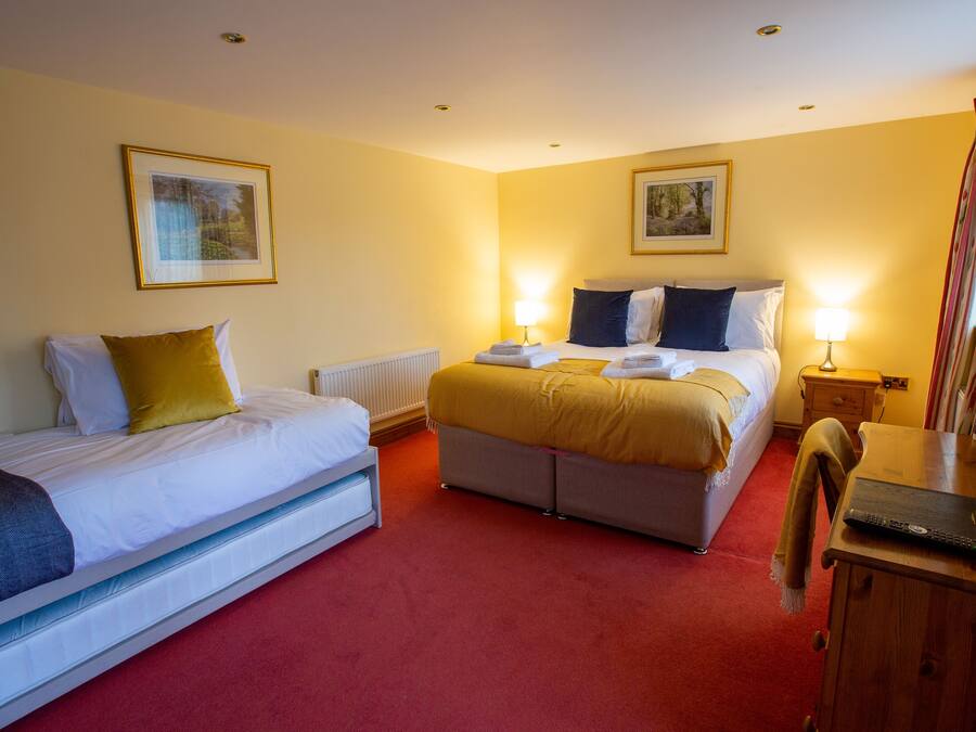 A hotel room with two beds, a wooden desk, and a mirror.