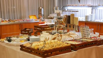 Um buffet com diversas opções de comida, incluindo pães, doces e bebidas.