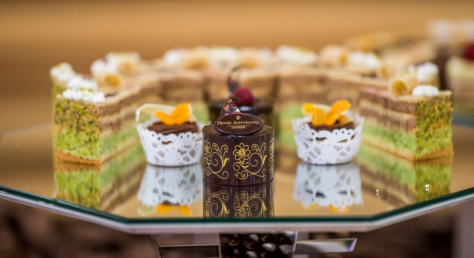 Una presentación de postres con varios pasteles y dulces sobre una mesa de cristal.