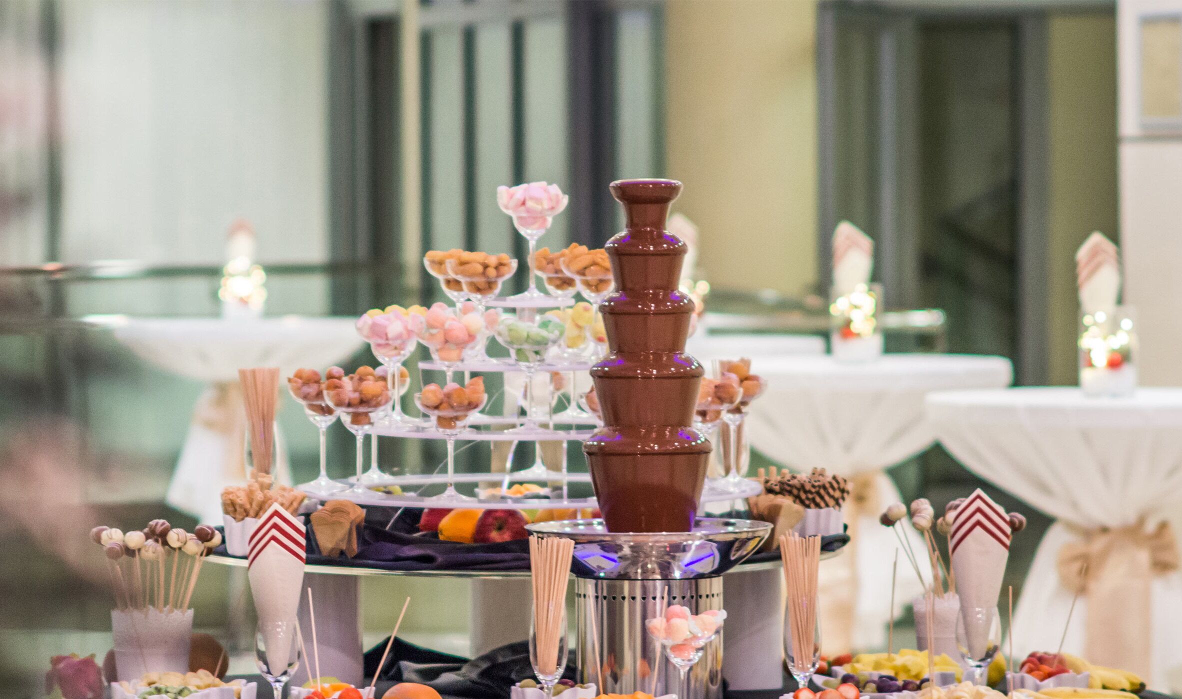 Una mesa de postres con varios niveles de dulces y una fuente de chocolate.