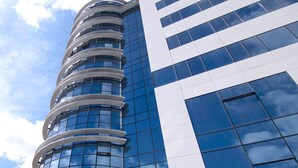 Un bâtiment moderne doté d’une façade en verre incurvée et d’un logo en forme de « H » bien visible sur le dessus.