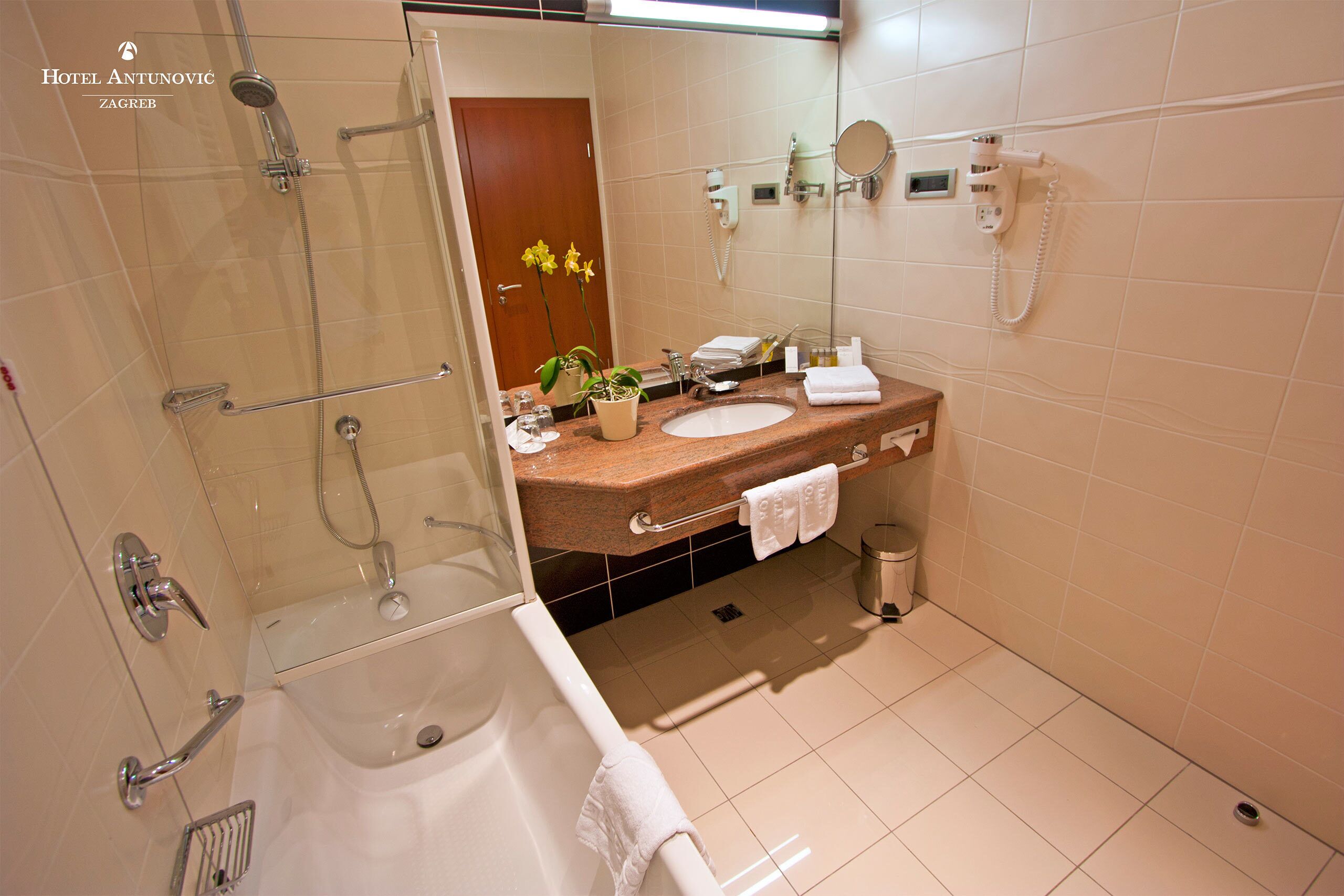 Un baño moderno con bañera, ducha, lavabo con espejo e inodoro.