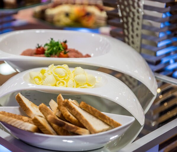 Un buffet proposant divers plats, notamment du pain, du beurre et un plat agrémenté d’une garniture.
