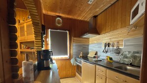 A compact kitchen with wooden cabinets, a black countertop, and a window with blinds. - House on the edge of the forest with sauna and view over the Rhine Valley (Weyer)