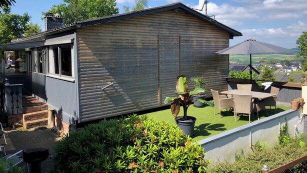A small wooden cabin with a patio area, a satellite dish, and a view of the surrounding landscape. - House on the edge of the forest with sauna and view over the Rhine Valley (Weyer)