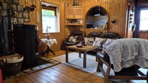 A cozy cabin interior with a fireplace, wooden walls, a leather sofa, and a dining table. - House on the edge of the forest with sauna and view over the Rhine Valley (Weyer)