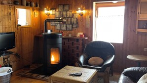 A cozy cabin interior with a wood-burning stove, leather furniture, and a television. - House on the edge of the forest with sauna and view over the Rhine Valley (Weyer)