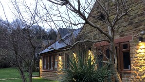 A stone house with a well-maintained garden and a large agave plant in the foreground. - Wisteria Cottage - Cotswolds (Warmington)