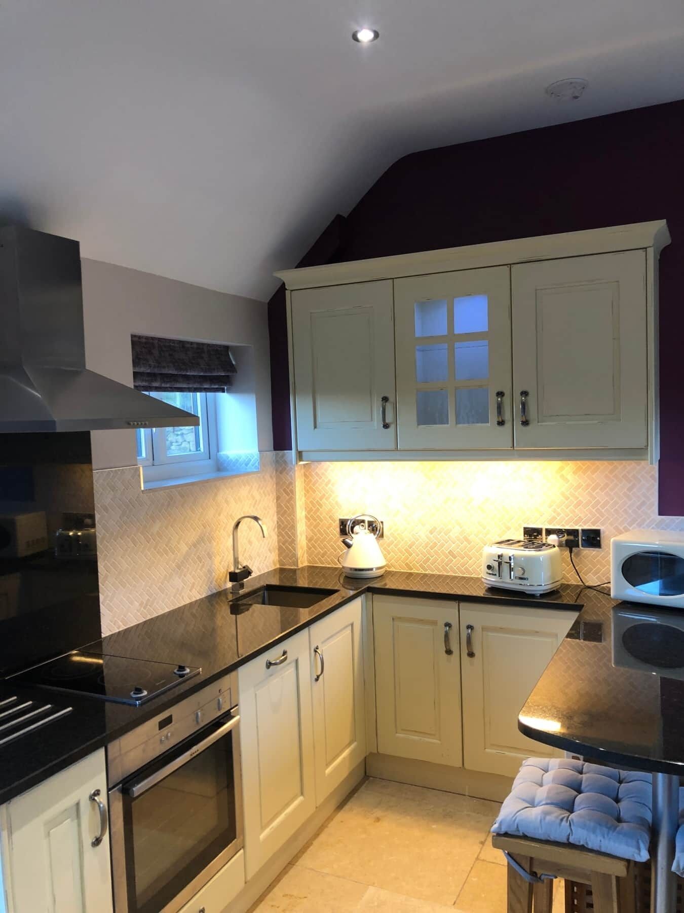 A kitchen with white cabinets, a black countertop, a stove, and a microwave.