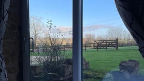 A bedroom with a large sliding glass door leading to a grassy outdoor area. - Wisteria Cottage - Cotswolds (Warmington)