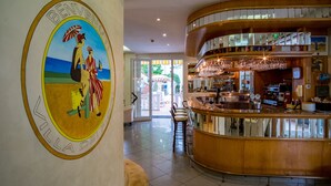 A hotel lobby with a bar area, a reception desk, and a large emblem on the wall. - Hotel Villa dei Fiori (Rimini)
