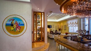 A hotel lobby with a large mural, a bar area with a wine glass, and a staircase leading to another level. - Hotel Villa dei Fiori (Rimini)