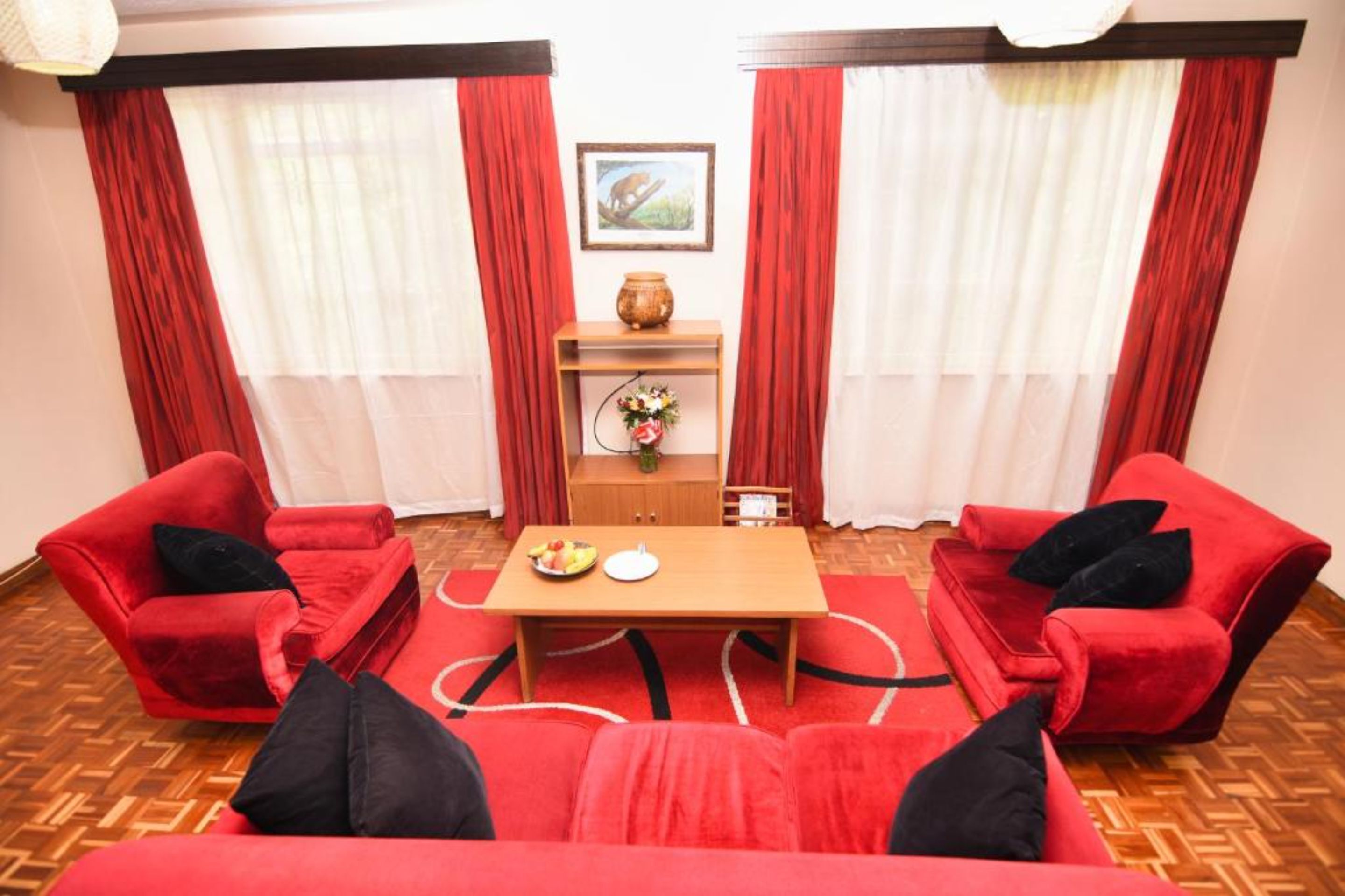 Ein Zimmer mit einem roten Sofagarnitur, einem Holztisch und einer kleinen Kommode mit einer Vase.