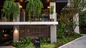 A modern building entrance with a sign indicating directions to the lobby and parking. - Gardina Asoke Hotel & Residence (Bangkok)
