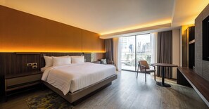 A modern hotel room with a large bed, a desk, and a chair.