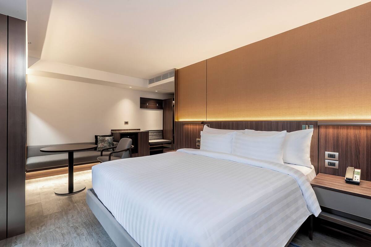 Una habitación de hotel moderna con una cama grande, un escritorio y una zona de estar.