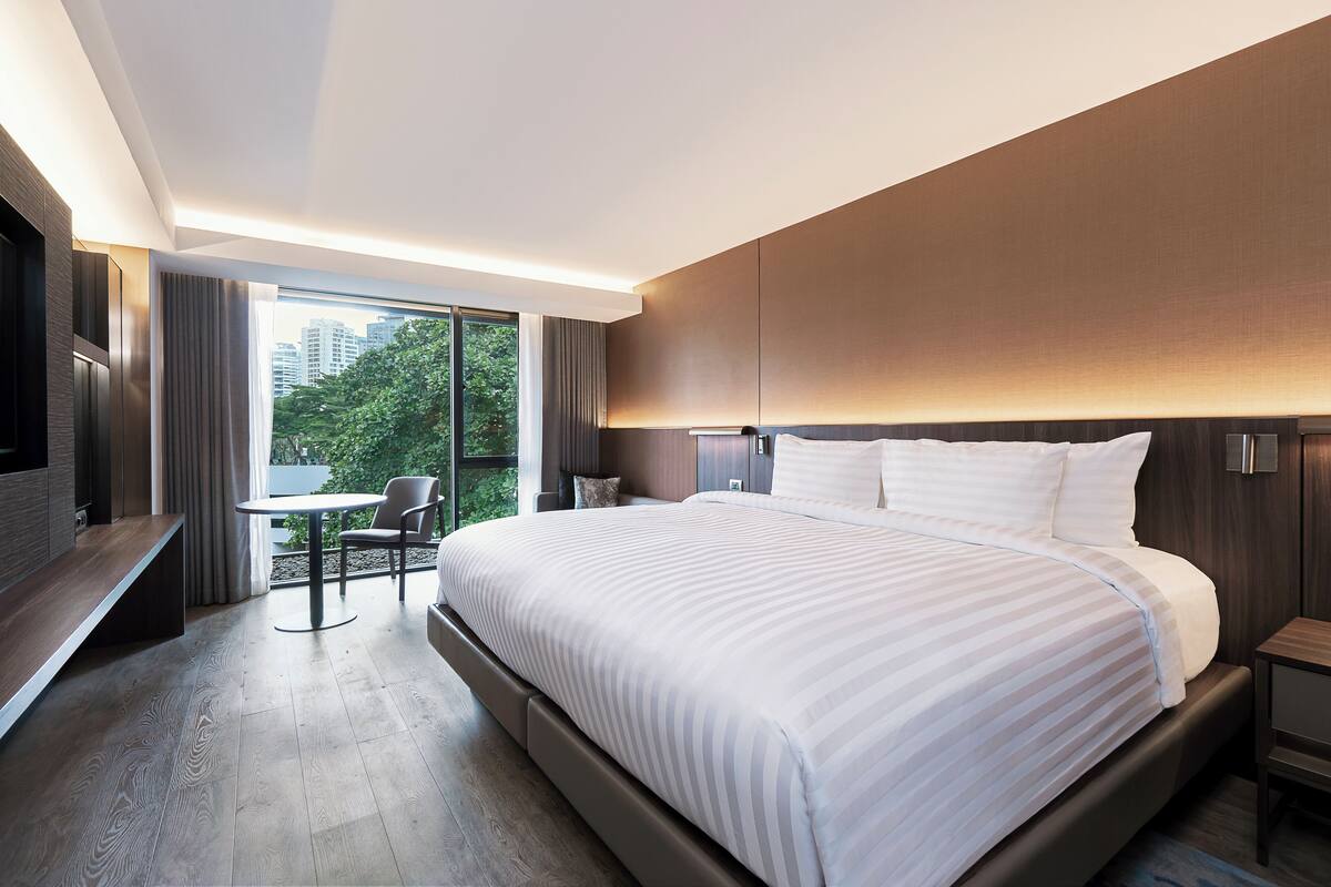 Una habitación de hotel moderna con una cama grande, un escritorio y vistas a zonas verdes.