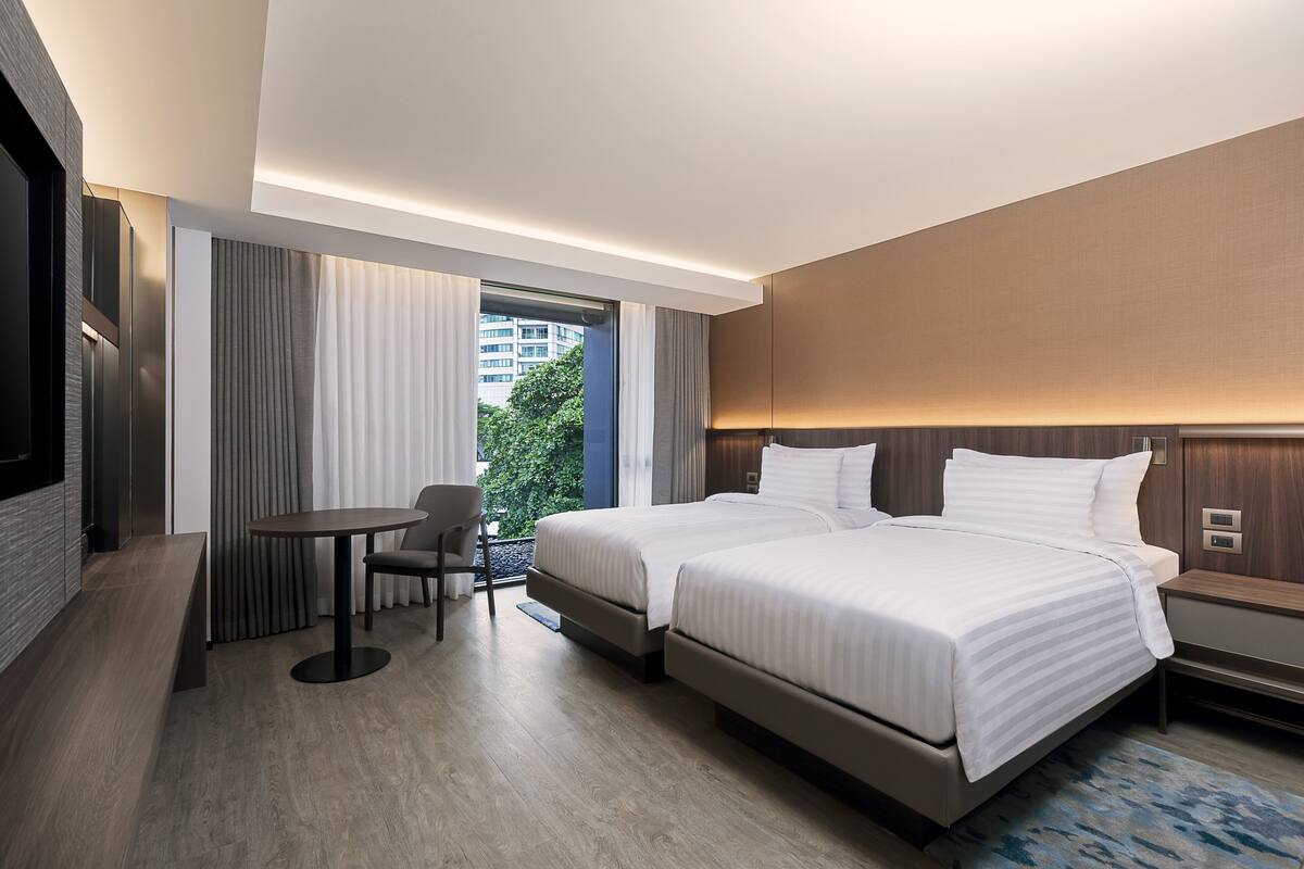Una habitación de hotel moderna con dos camas, un escritorio y una silla.