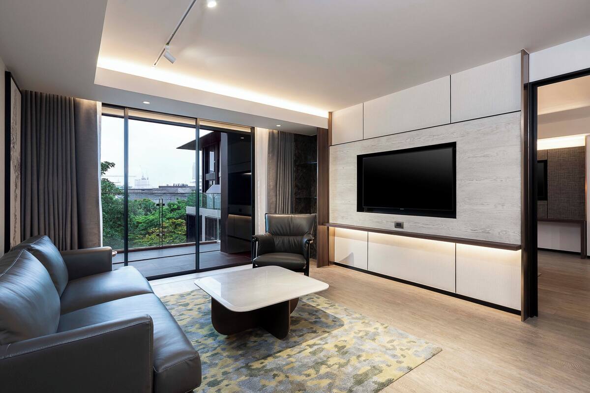 Una sala de estar moderna con un sofá de cuero, una mesa de centro y un televisor de pantalla plana montado en la pared.
