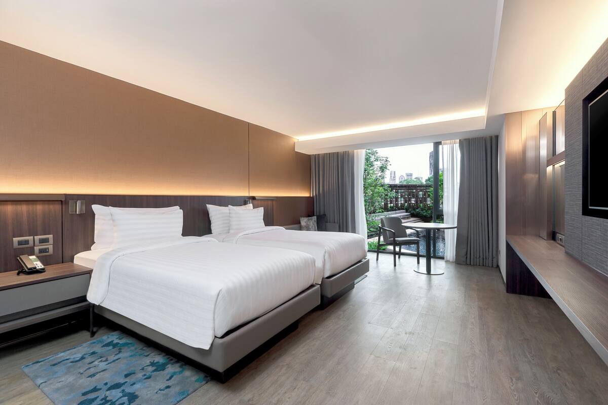 Una habitación de hotel moderna con una cama grande, mesitas de noche, un escritorio y un televisor.