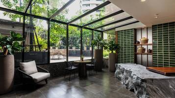 A modern interior with a glass wall, a stone counter, and a seating area with chairs and a table.