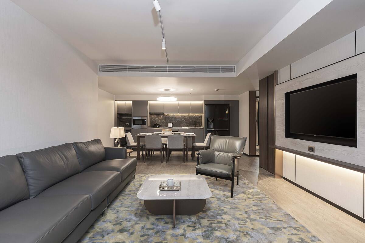 Una sala de estar moderna con un sofá gris, una mesa de centro y un televisor de pantalla plana montado en la pared.
