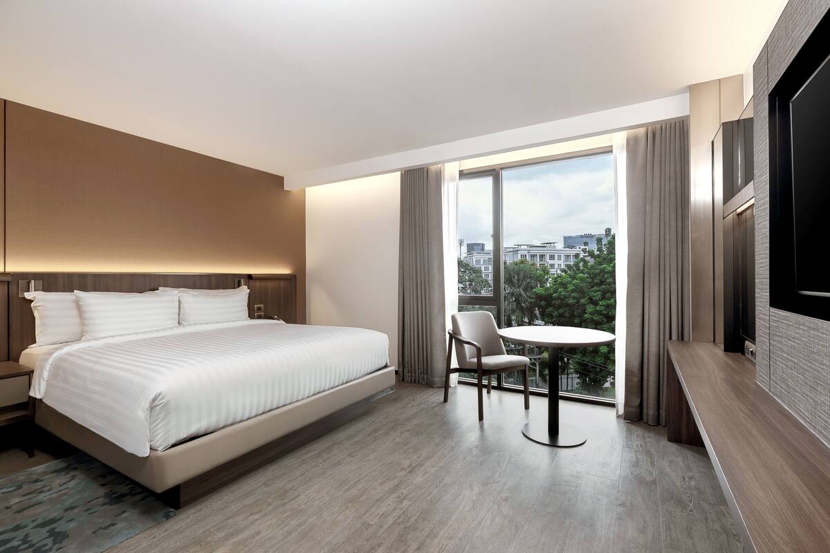 Una habitación de hotel moderna con una cama grande, una mesa redonda y un televisor.