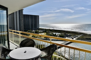 Enjoy the ocean view from this balcony with wicker furniture and a small table.