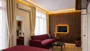 A hotel room with two beds, a sofa, a TV, and a mirror. - Zebra Hotel Alsancak (Izmir)