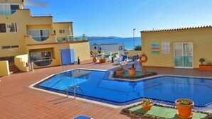 Un espace piscine comprenant deux piscines, des chaises longues et des plantes en pot.