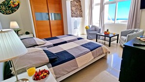 Une chambre d’hôtel avec un lit, un bureau, une chaise, une télévision et une vue sur l’océan.