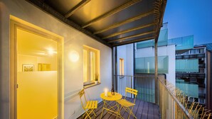 A balcony with a wooden floor, yellow chairs, and a table. - Jimmy's Apartments Dandelion (Vienna)