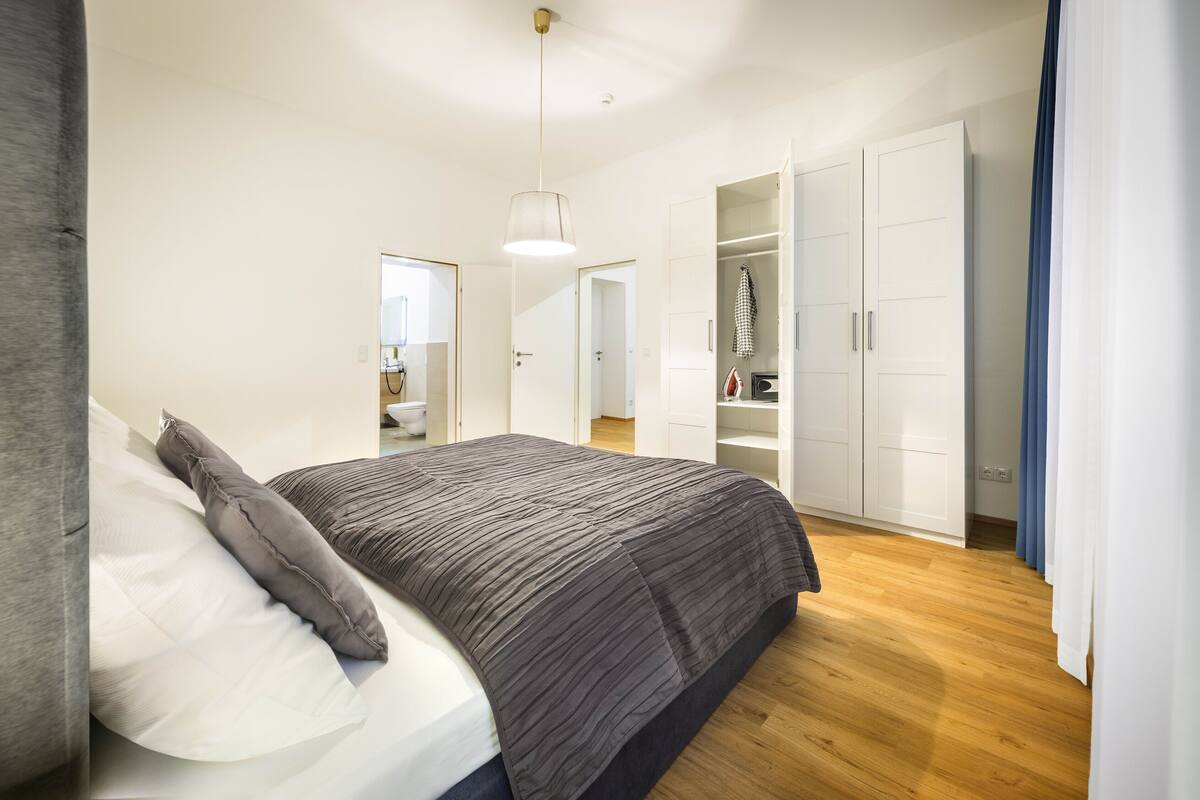 A bedroom with a bed, a wardrobe, and a hanging light fixture.