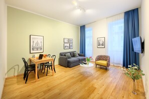 A living room with a dining area, a sofa, a TV, and framed pictures on the wall.