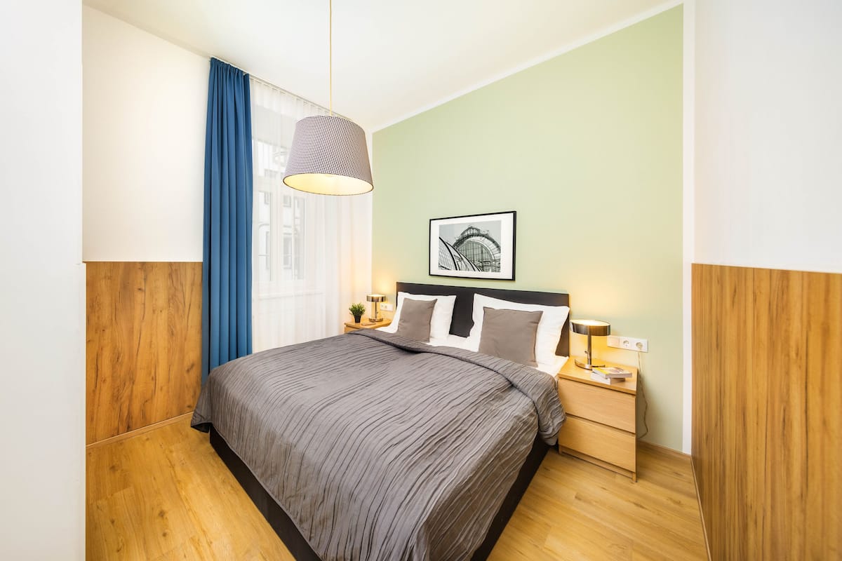 A neatly arranged bedroom with a bed, bedside tables, a lamp, and a framed picture on the wall.