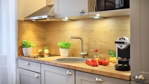 A modern kitchen with a stainless steel sink, wooden countertop, and built-in cabinets. - Jimmy's Apartments Dandelion (Vienna)