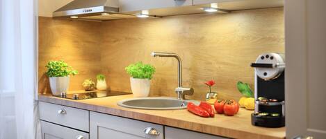 A modern kitchen with a stainless steel sink, wooden countertop, and built-in cabinets.