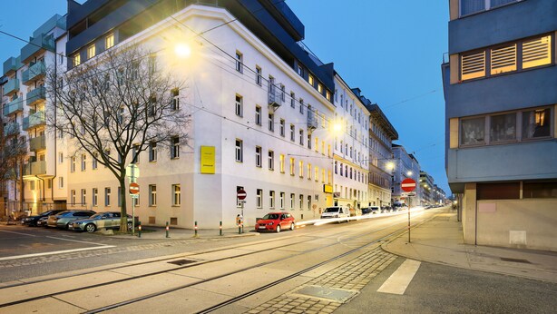 A multi-story building with a white facade, multiple balconies, and a tram line running in front. - Jimmy's Apartments Dandelion (Vienna)