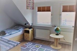 A child's bedroom with a bunk bed, a desk, a globe, and a window with blinds.