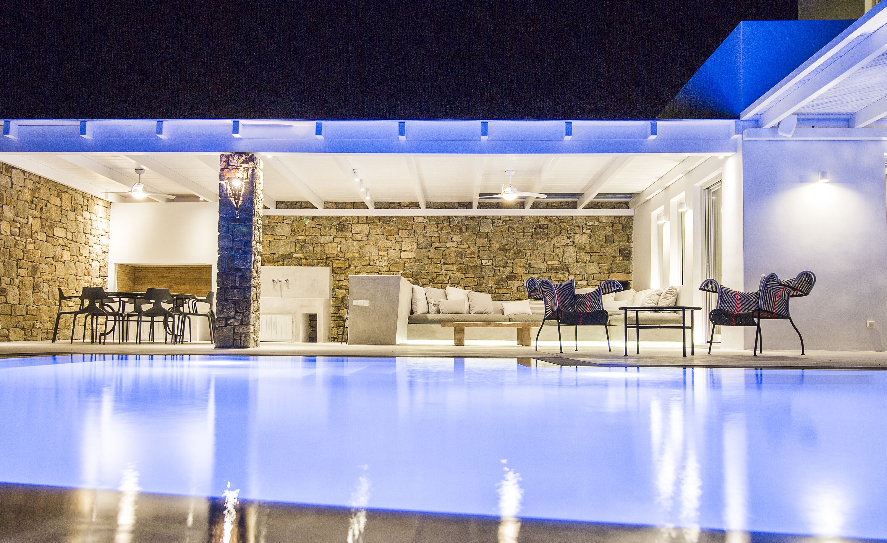 An indoor swimming pool with stone walls and modern furniture.