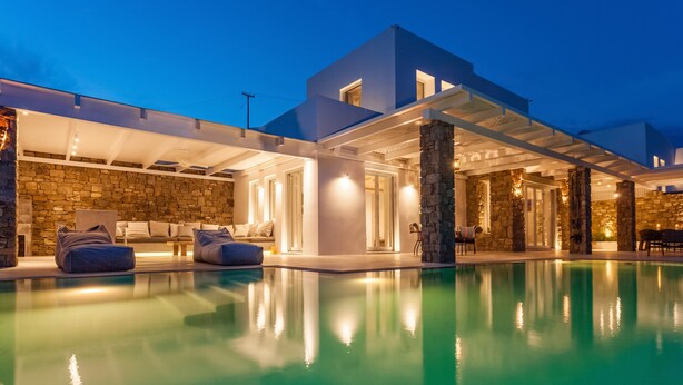 A modern house with a swimming pool, stone walls, and outdoor seating.