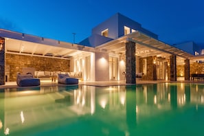 Ein modernes Haus mit Swimmingpool, Steinwänden und Sitzgelegenheiten im Freien.