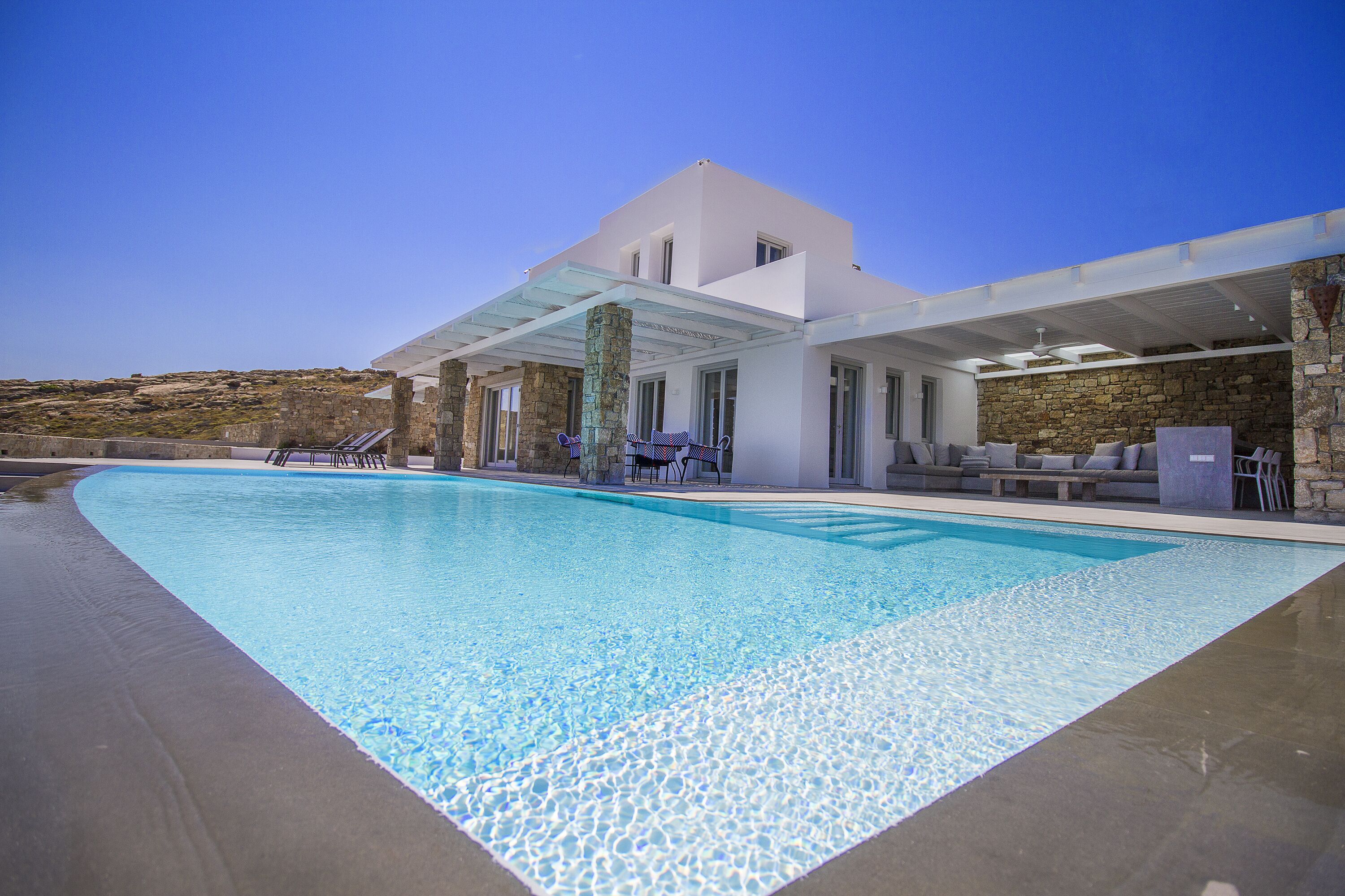 A modern house with a swimming pool, stone walls, and outdoor furniture.