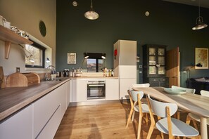 Une cuisine moderne avec des meubles blancs, un plan de travail en bois et un coin repas avec des chaises blanches.
