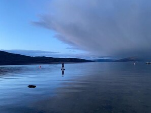 A calm lake with a person standing on the shore, surrounded by hills and a cloudy sky. - The Moorings, overlooking Loch Fyne - sleeps 4 guests  in 2 bedrooms (Cairndow)