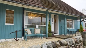 A blue house with a stone wall in front, a bench, and a small tree. - The Moorings, overlooking Loch Fyne - sleeps 4 guests  in 2 bedrooms (Cairndow)
