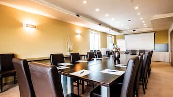A conference room with a long table, chairs, a projector screen, and a whiteboard.