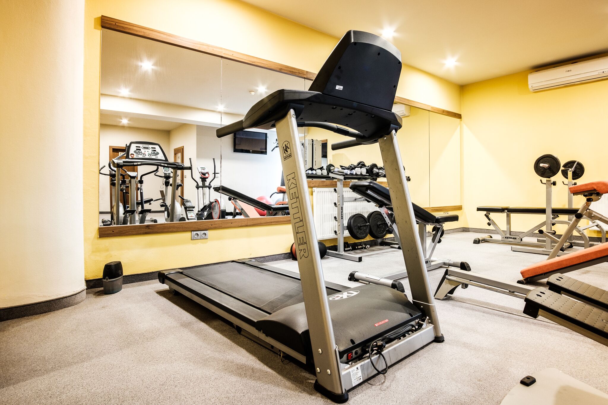 A gym with a treadmill, weight bench, and various exercise equipment.