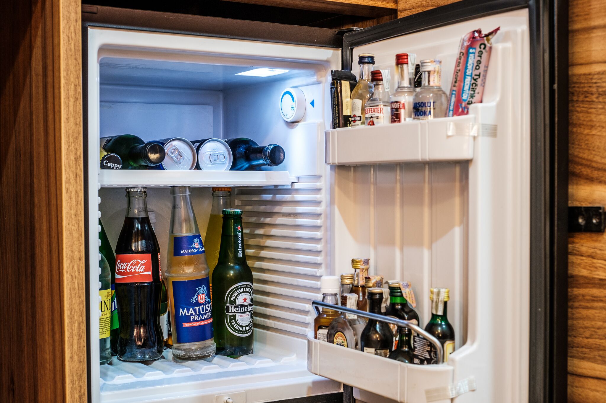 Un refrigerador abierto repleto de diversas bebidas, incluyendo botellas de Coca-Cola, Matzá y Heineken.