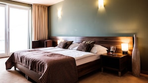 Una habitación de hotel con una cama grande, una mesita de noche con lámpara y un jarrón.